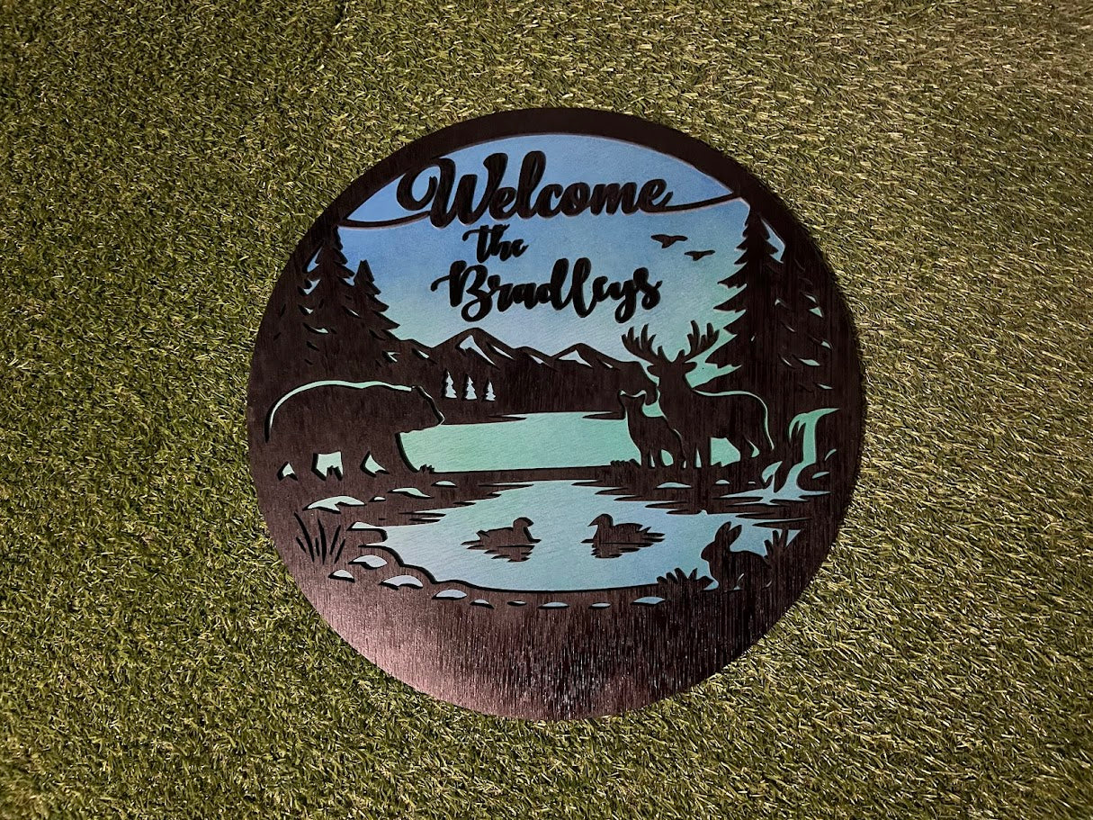 Decorative metal sign with nature-themed design and 'Welcome the Bradleys' text on a textured surface.