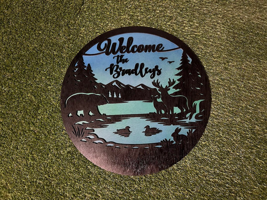 Decorative metal sign with nature-themed design and 'Welcome the Bradleys' text on a textured surface.